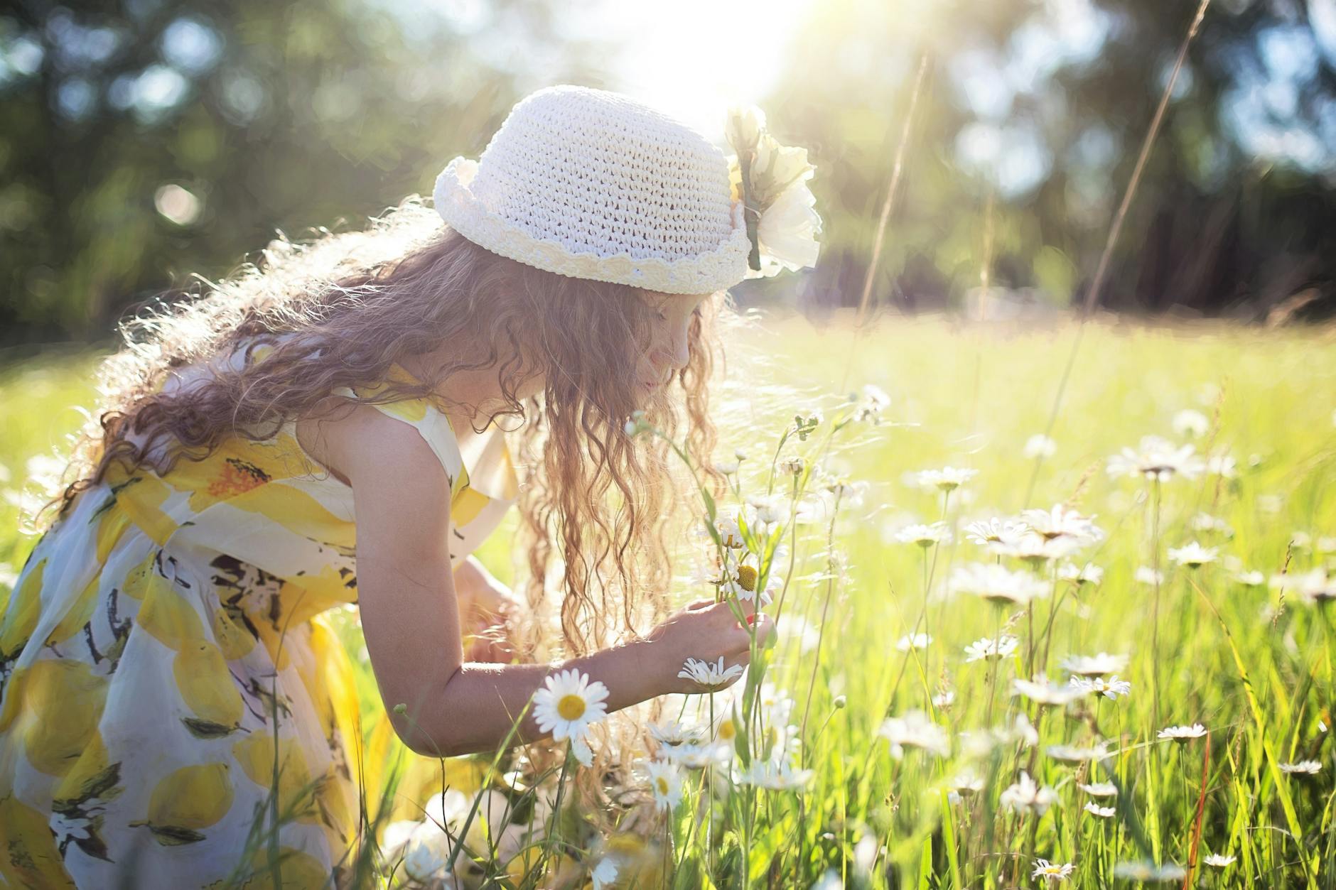 girl picking flowers for a summer solstice ritual, celebrating Litha