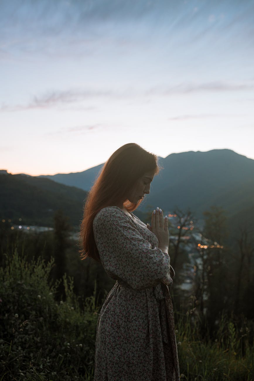 woman standing while praying outdoors, considering wants vs needs and opportunities for peace via common ground during times of unrest