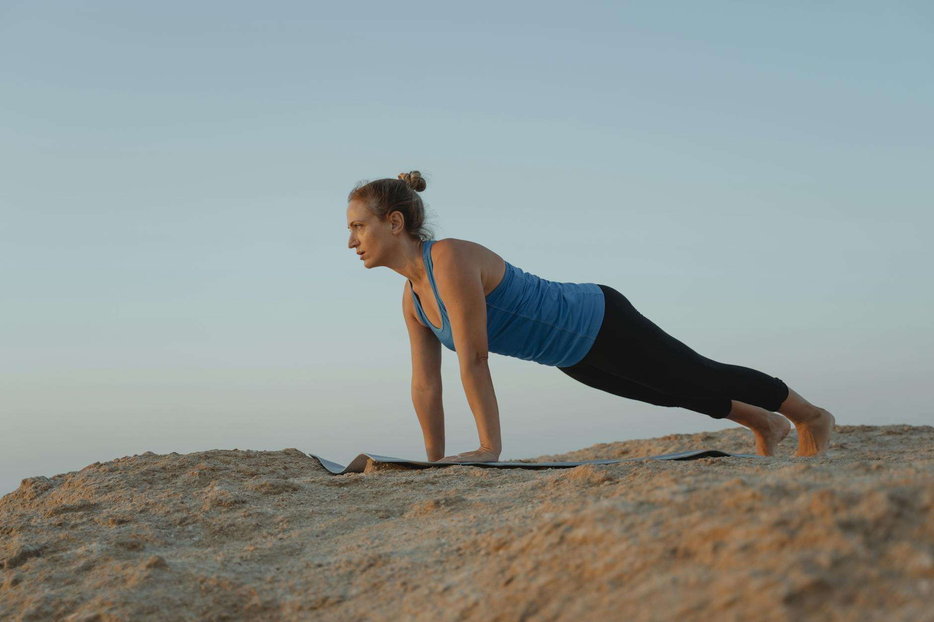 woman doing a summer yoga flow, surya namaskar, for solar energy alignment while celebrating Litha; summer solstice sun salutations