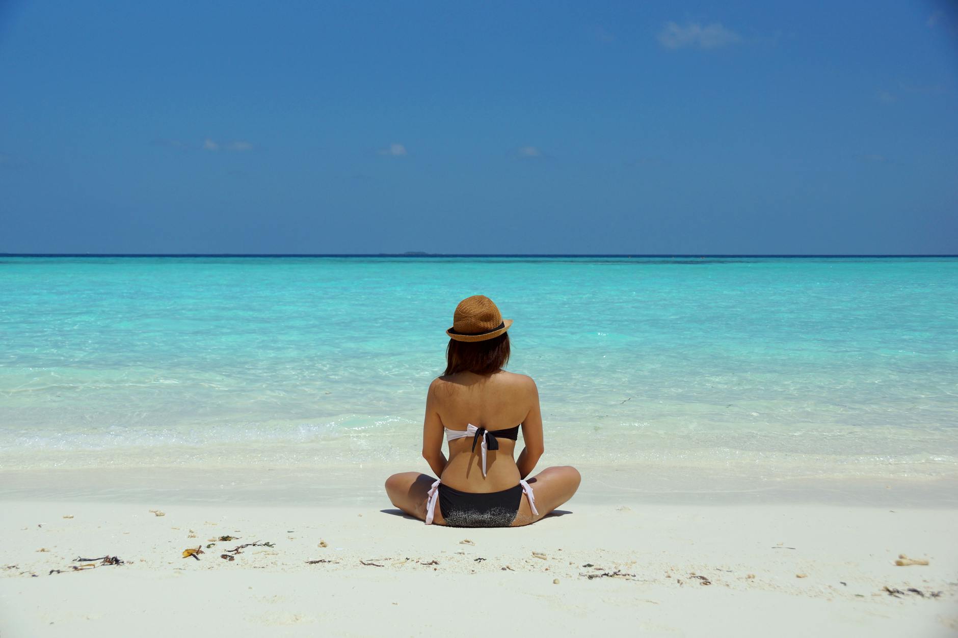 woman wearing black and white brassiere sitting on white sand, exploring types of meditation and meditation techniques, as well as the benefits of meditation, mindfulness meditation, and how to meditate