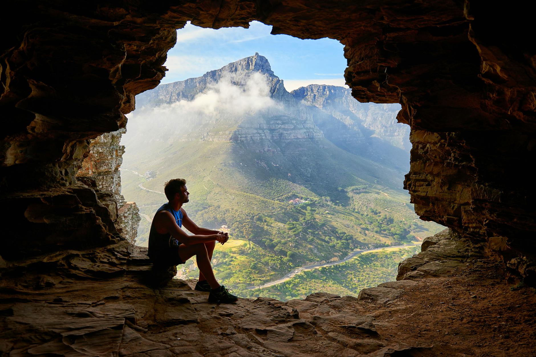 photo of man sitting on a cave, considering spiritual connection, meditation practice, mindfulness and intuition, connect with higher self, and meditation for inner peace