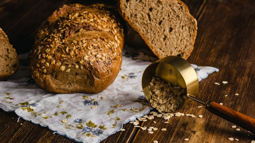 rustic bread and oats on wooden table; Lammas bread from a Lughnasadh recipe, for the first harvest Sabbat; in Lammas traditions, bake Lammas bread