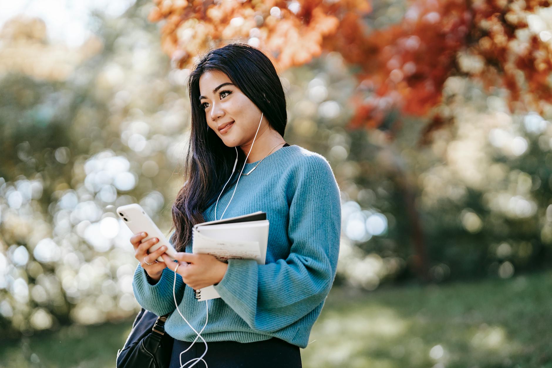 young woman enjoying music using smartphone in garden, practicing mindfulness, mindfulness in relationships, mindfulness at work, mindful communication, and daily mindfulness