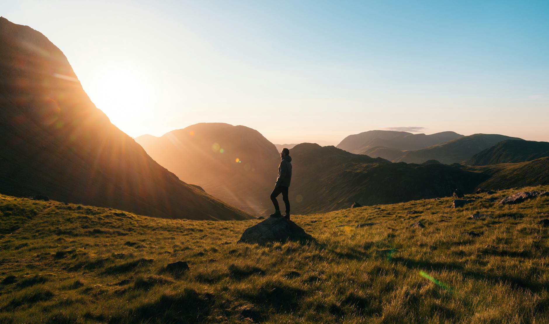 silhouette photography of person standing on green grass in front of mountains during golden hour, contemplating meditation for daily life, mindfulness routines, daily meditation practice, mindfulness habits, and how to integrate meditation