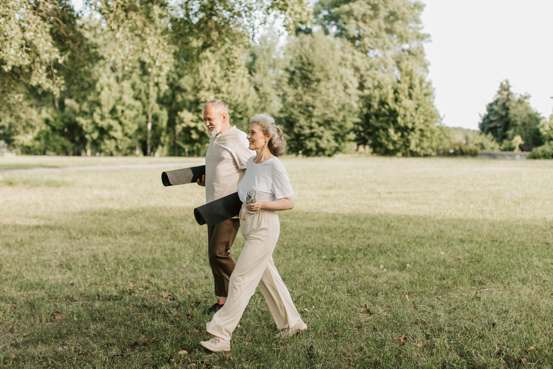 an elderly man and woman carrying yoga mats while walking, considering meditation hurdles, consistent practice, sustain mindfulness, meditation obstacles, and how to meditate consistently.