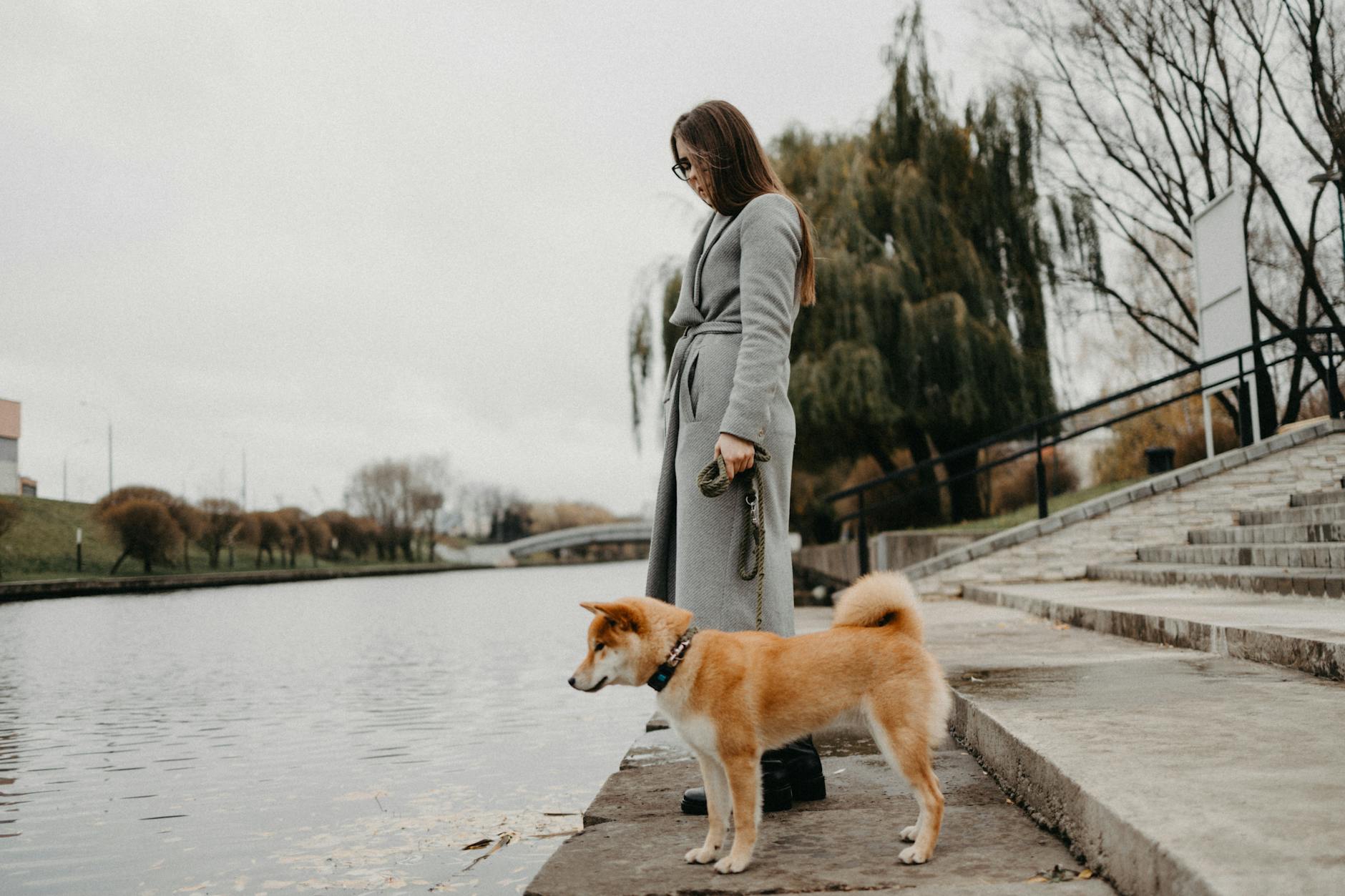 a woman with a dog by a river, considering meditation hurdles, consistent practice, sustain mindfulness, meditation obstacles, and how to meditate consistently.