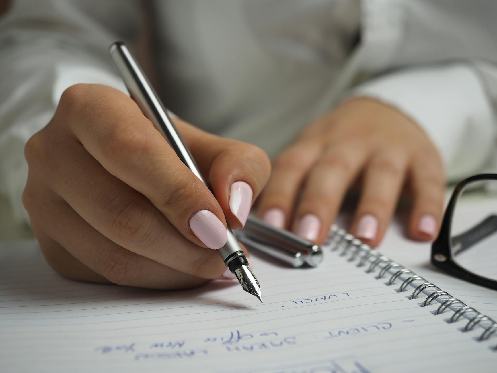 woman in white long sleeved shirt holding a pen writing on a paper, illustrating Virgo, Wheel of the Year, Hellenistic Astrology, Mutable Earth, and Virgo Season