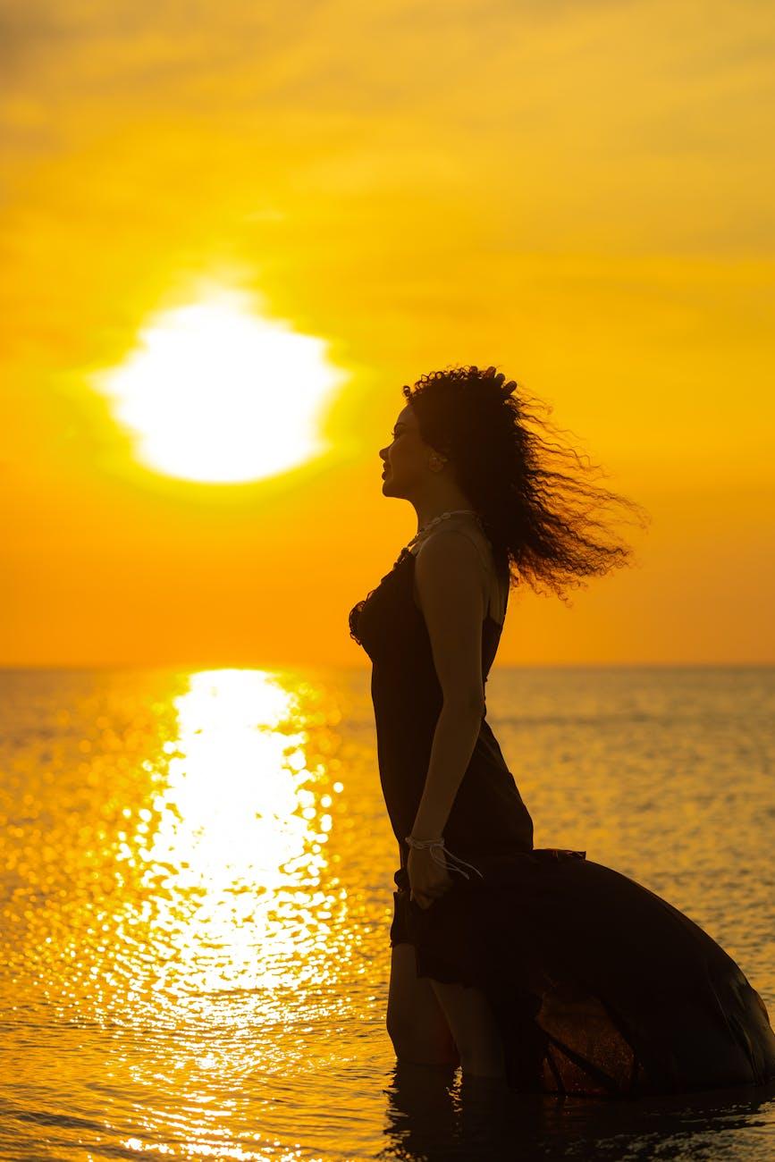 silhouette of woman at sunset by the sea, illustrating spiritual growth, meditation, awareness, ego transcendence, and intuitive wisdom