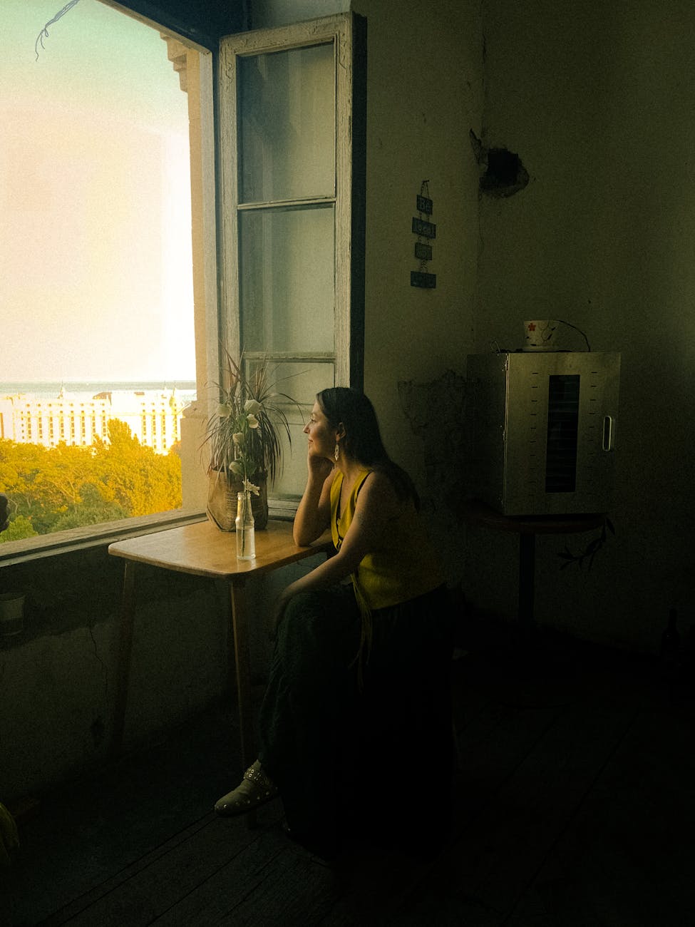reflective woman sitting by sunny window in baku, illustrating spiritual growth, meditation, awareness, ego transcendence, and intuitive wisdom