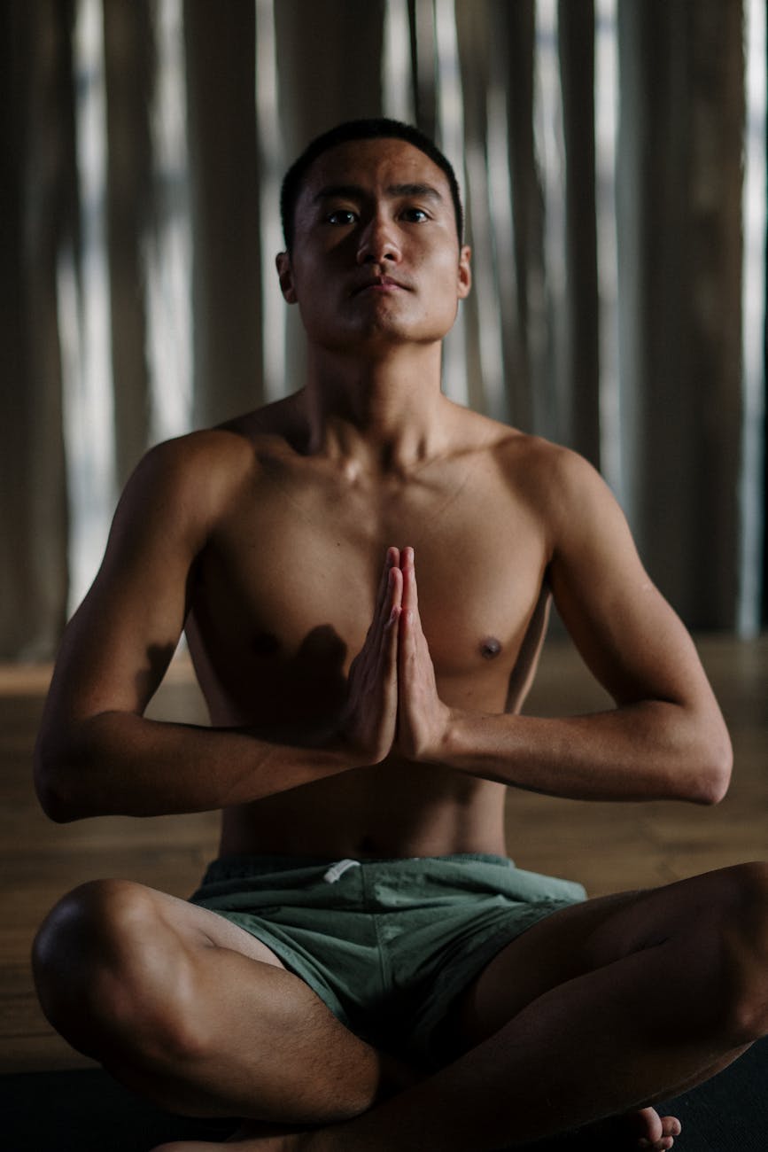 topless man in green shorts sitting on brown couch, illustrating spiritual growth, meditation, awareness, ego transcendence, and intuitive wisdom