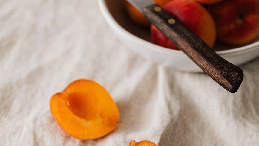 delicious peaches and knife on white tablecloth for first harvest, Lammas reflections, celebrating Lughnasadh, summer harvest, gratitude ritual
