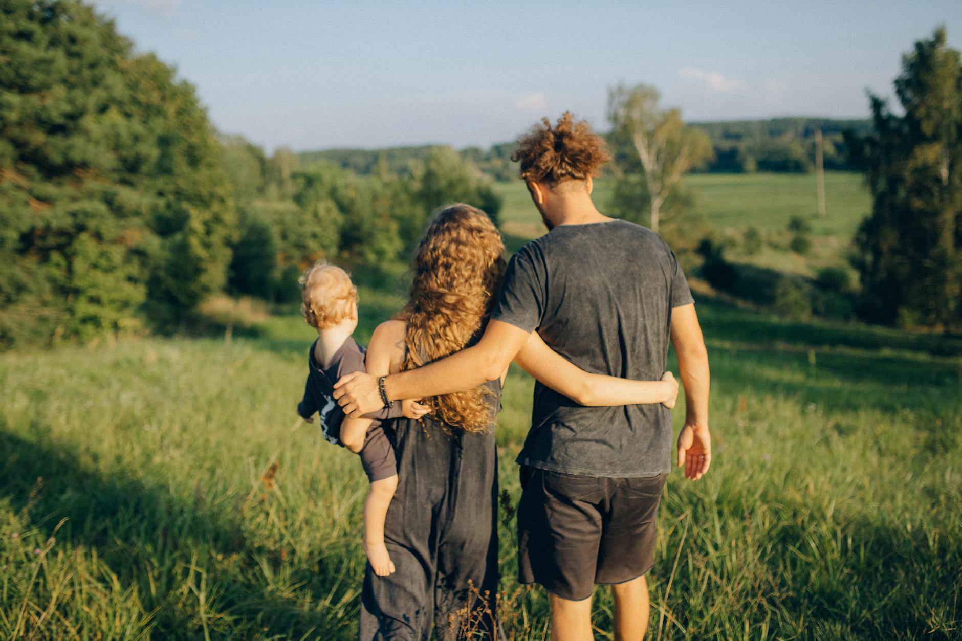 back view of a family walking on the green grass, showing the importance of interconnectedness, meditation, oneness, unity and compassion, and connection with nature