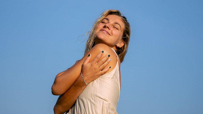 a woman with her eyes closed under a blue sky, illustrating Pranayama, breathing techniques, breath control for meditation, meditation for energy and calm, and advanced breathing exercises