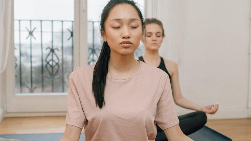 women sitting on yoga mat while meditating with their eyes closed, evoking advanced meditation techniques, deep meditation practice, meditation journey, advanced mindfulness, and spiritual growth meditation