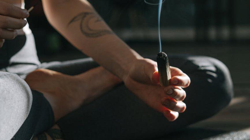a person in black tank top holding a wooden stick, illustrating lasting wellbeing, benefits of meditation, stress relief, emotional resilience, and mind-body connection