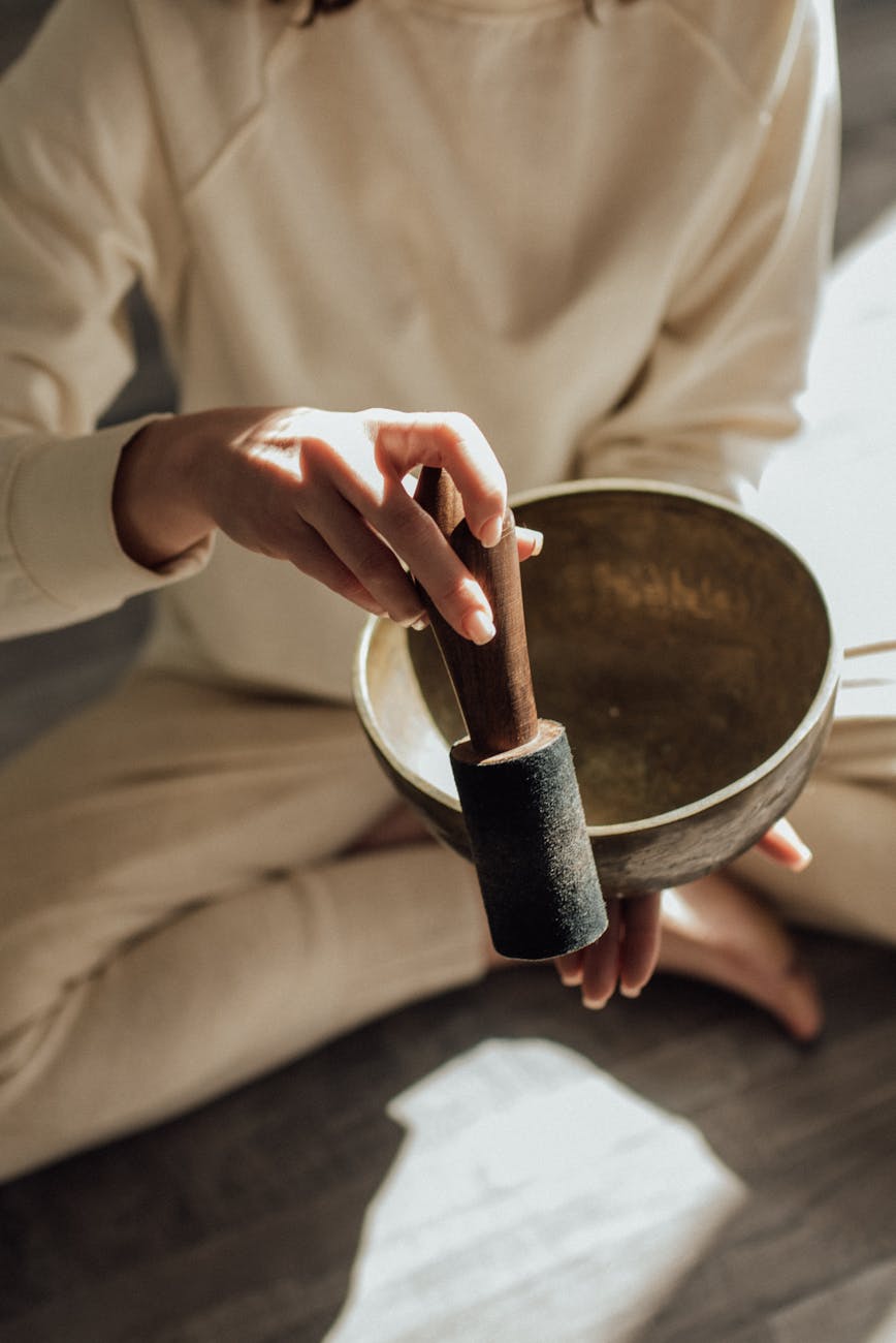 a person holding a mallet and a singing bowl, evoking advanced meditation techniques, deep meditation practice, meditation journey, advanced mindfulness, and spiritual growth meditation