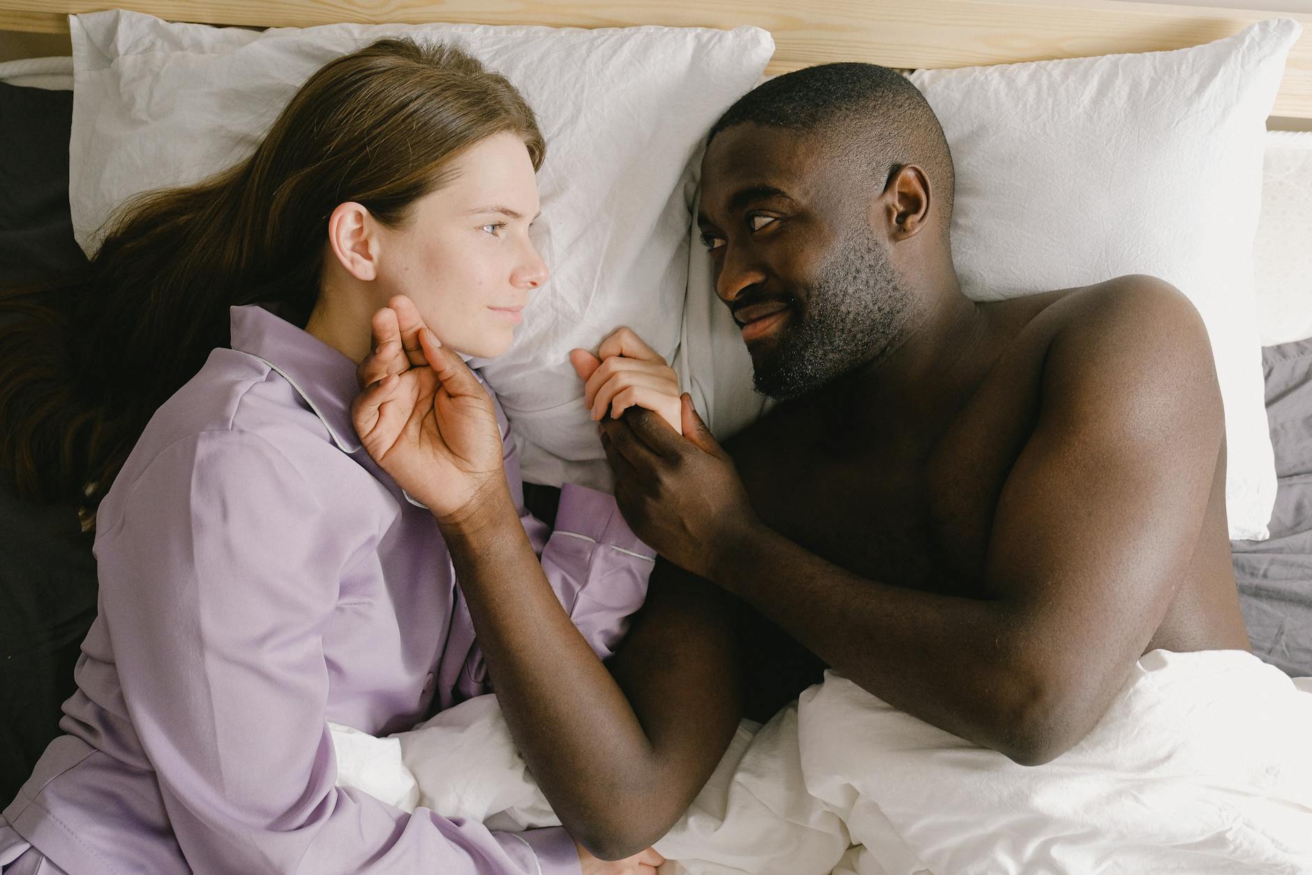 couple lying on bed while looking face to face, illustrating lasting wellbeing, benefits of meditation, stress relief, emotional resilience, and mind-body connection