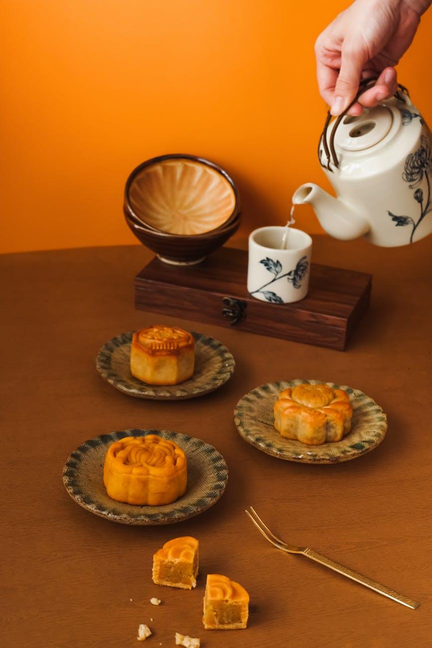 woman hand pouring water from kettle to cup near cakes on plates, , illustrating: moon rituals, lunar traditions, modern moon practices, lunar guidance, and intention setting rituals