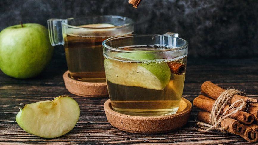 photo of slice green apple and cinnamon stick, illustrating: how to Celebrate Mabon, spiced apple cider recipe, autumn ritual, seasonal drink, and the Wheel of the Year