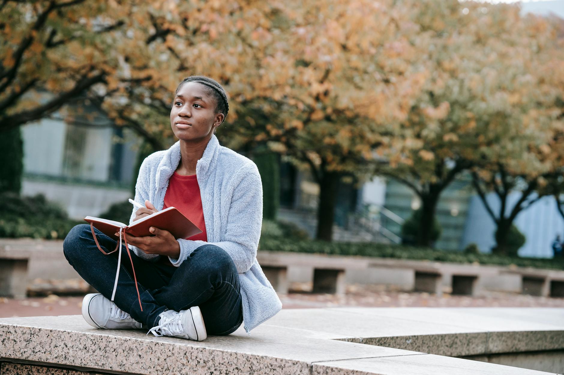dreamy black student with diary in urban park, illustrating: Mabon divination, inner wisdom, Tarot spread, harvest reflection, and the Autumn Equinox