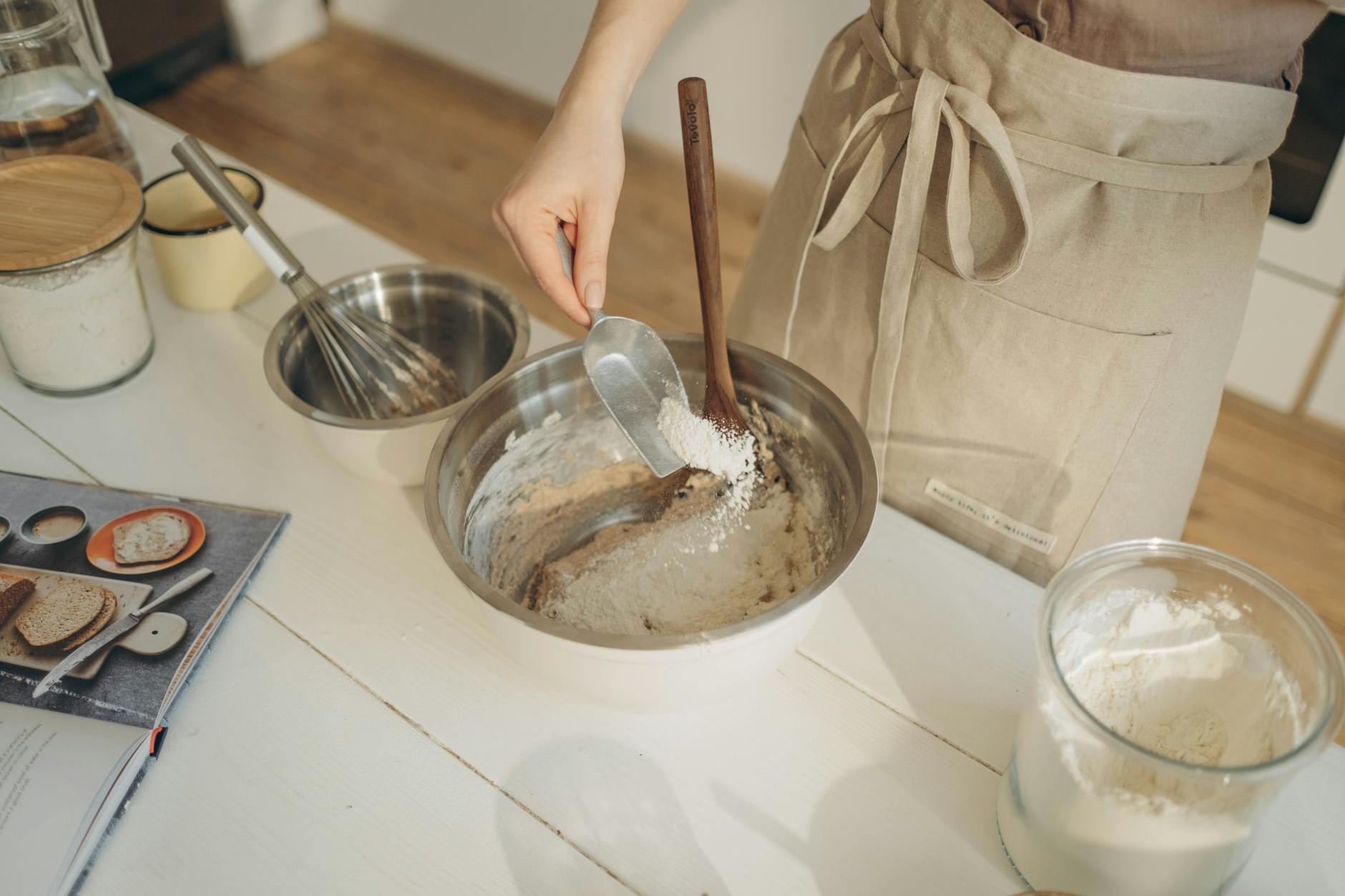 a person pouring flour into the bowl using a measuring spoon, illustrating: a feast ritual, sacred eating, Autumn Equinox, harvest celebration, and seasonal food