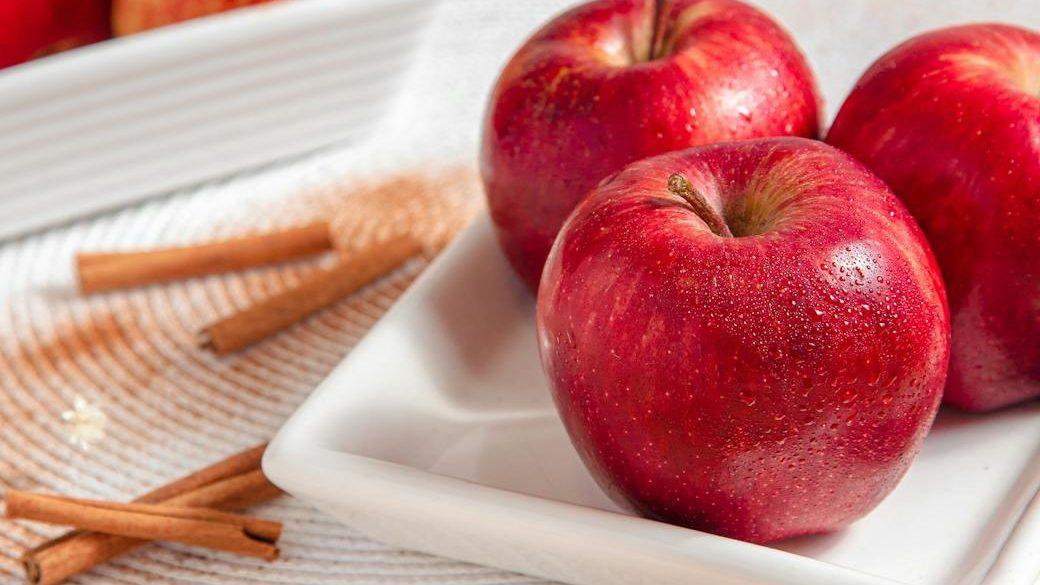 red apples on a ceramic plate near cinnamon sticks, illustrating: how to Celebrate Mabon, spiced apple cider recipe, autumn ritual, seasonal drink, and the Wheel of the Year