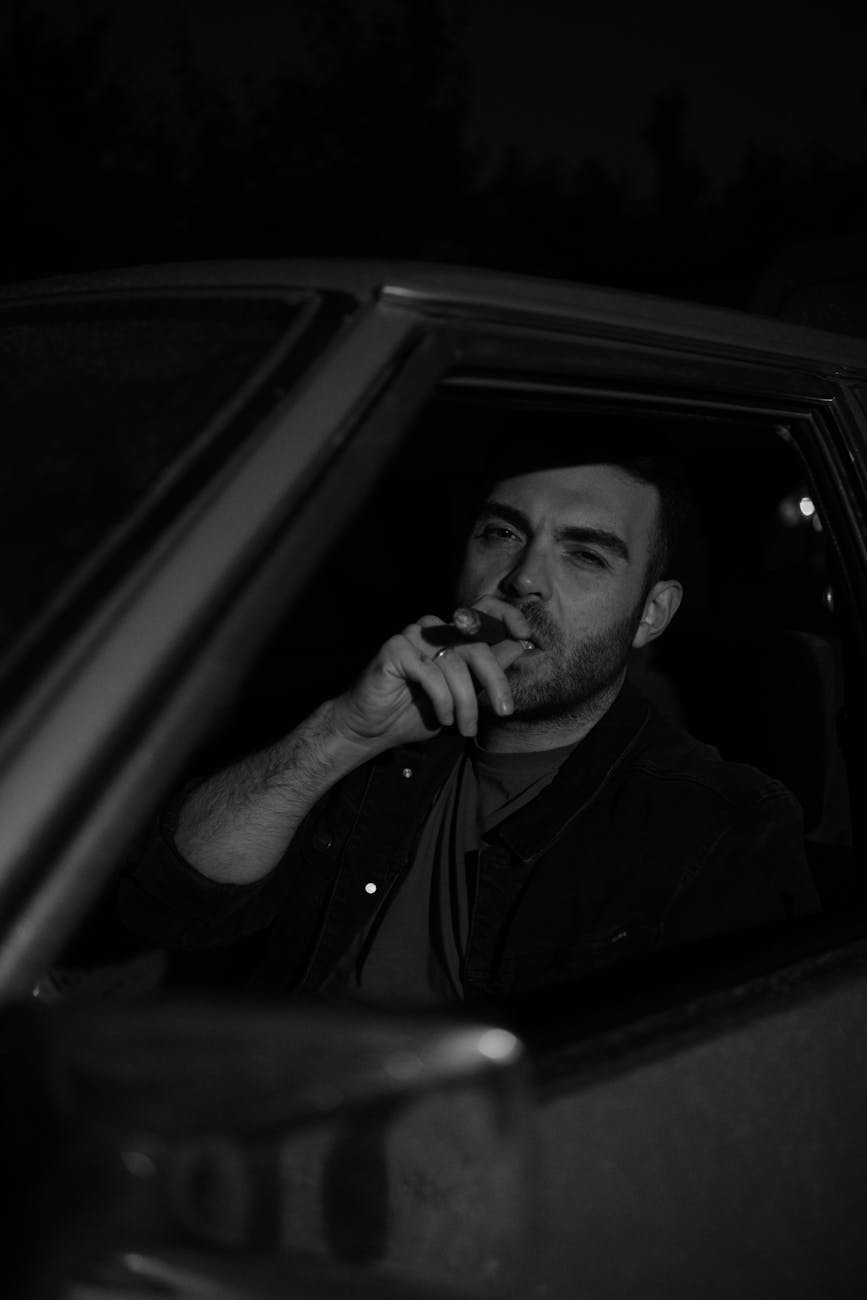 moody portrait of man smoking in car at night, illustrating: Scorpio, transformation, Scorpio season, Hellenistic astrology, and renewal